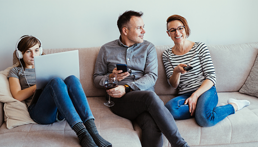 Parent and child sat on couch. Father is drinking